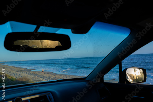 A couple embrace romantically on a California beach seen from a car interior photo