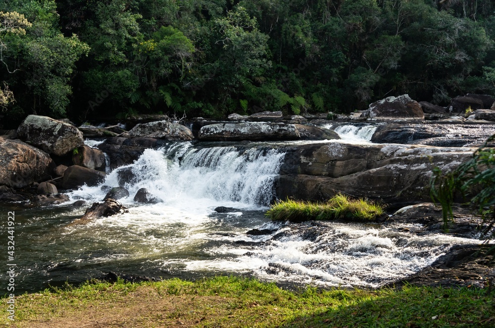 Fototapeta premium Paraibuna river crystal clear waters flowing around rock formations and creating a waterfall at the beginning of the hiking trail of the river in Cunha, Sao Paulo - Brazil.