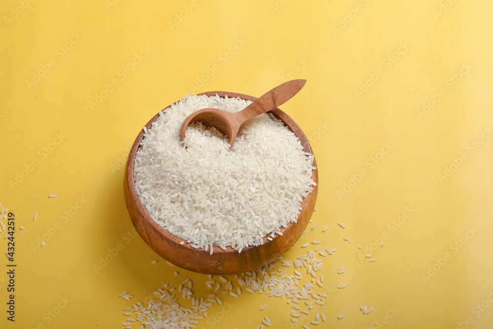 rice in a wooden bowl on a yellow background