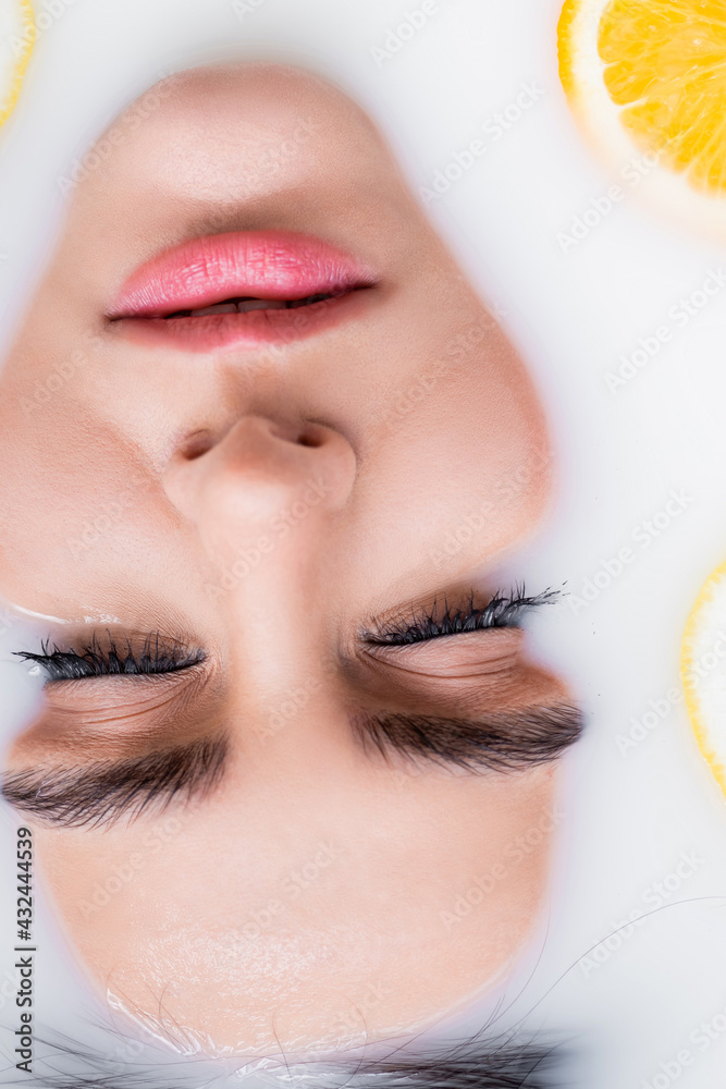 close up view of female face in bath with milk and sliced orange. close up view of female face in bath with milk and sliced orange.