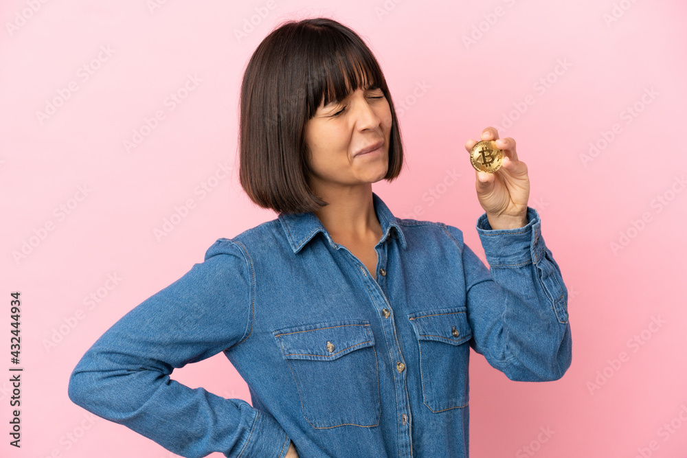 Young mixed race woman holding a Bitcoin isolated background suffering from backache for having made an effort