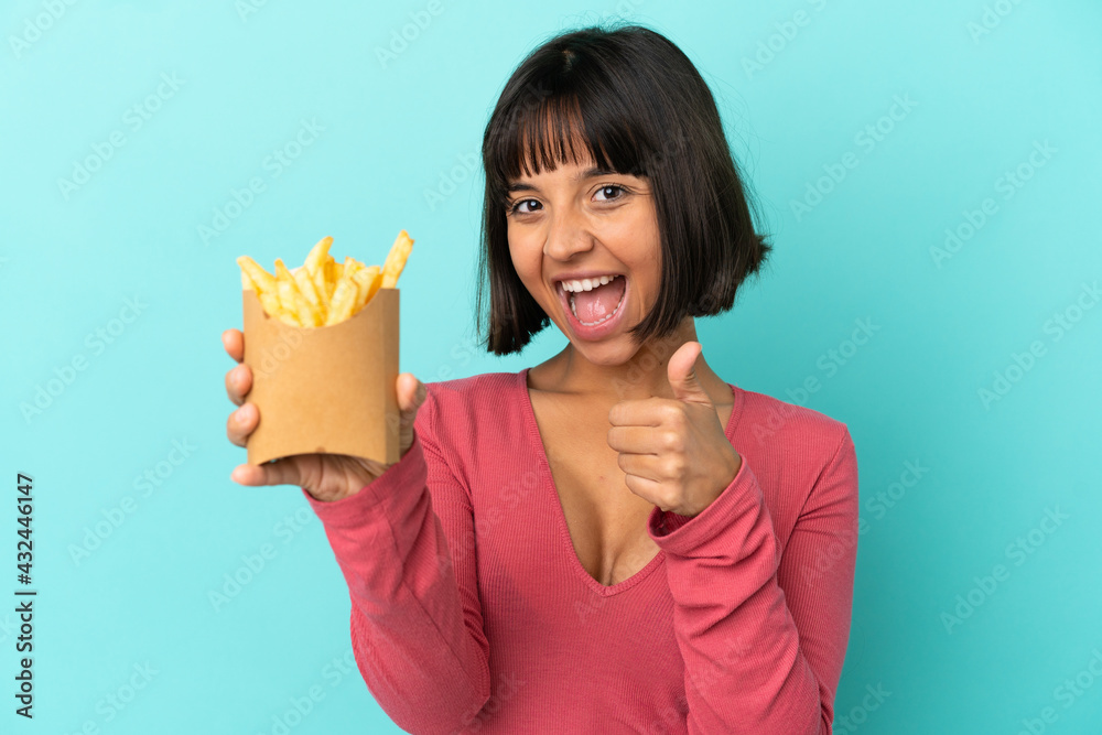 Young brunette woman holding fried chips over isolated blue background