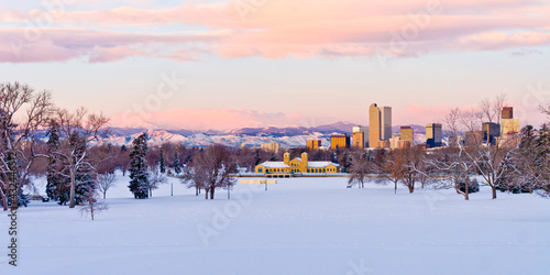 Downtown Denver Skyline from City Park at dawn on a cold January Morning with brightly lit pink and purple clouds over the foothills and the City Park Pavilion in the foreground with a snow covered pa photo