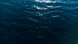 Aerial drone view of sea waves. Sun reflection on water surface. Disturbed ocean surface.  Deep blue sea.