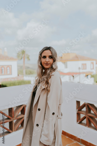 Obraz na płótnie chica joven sonriendo con vestido negro y gabardina marron posando sobre fondo d