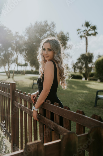 Chica adolescente mujer sonriendo rubia sentada en césped con arboles de fondo verde 