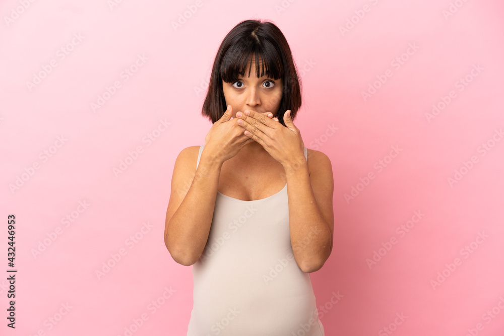 Young pregnant woman over isolated pink background covering mouth with hands