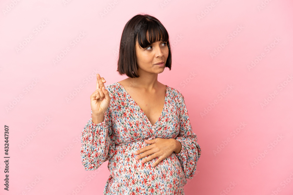Young pregnant woman over isolated pink background with fingers crossing and wishing the best Young pregnant woman over isolated pink background with fingers crossing and wishing the best