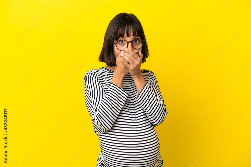 Young pregnant woman over isolated yellow background covering mouth with hands Young pregnant woman over isolated yellow background covering mouth with hands