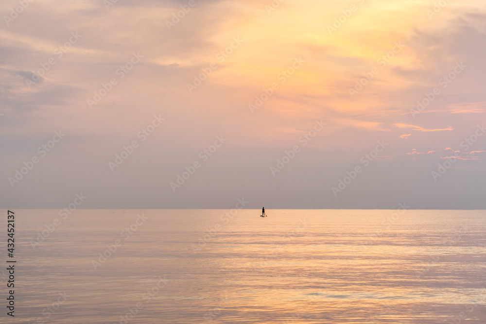 Silhouette woman stand up paddling on surfboard in sunrise