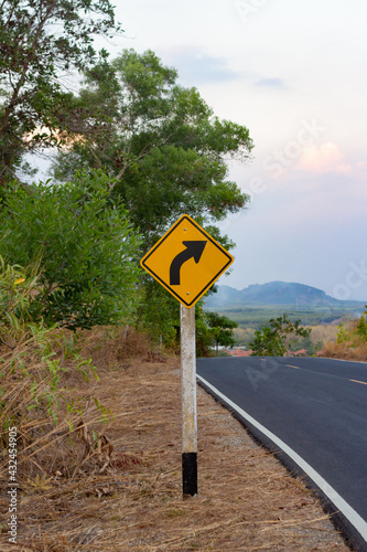 curvy road sign beside country road to the middle of city