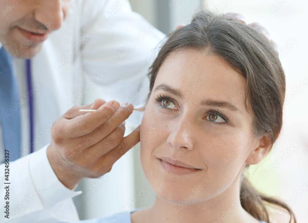 Doctor checking patients ear during medical examination. Doctor checking patients ear during medical examination.