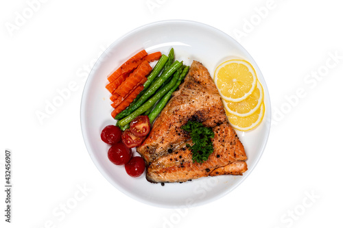 Salmon steak with vegetables, asparagus, carrots, green peas, lemon, pepper on isolated white background.