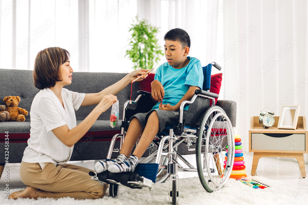 Portrait of asian physiotherapist carer helping and playing with special disabled child health problem by doing exercises sitting in wheelchair in rehabilitation clinic.disability care concept Portrait of asian physiotherapist carer helping and playing with special disabled child health problem by doing exercises sitting in wheelchair in rehabilitation clinic.disability care concept