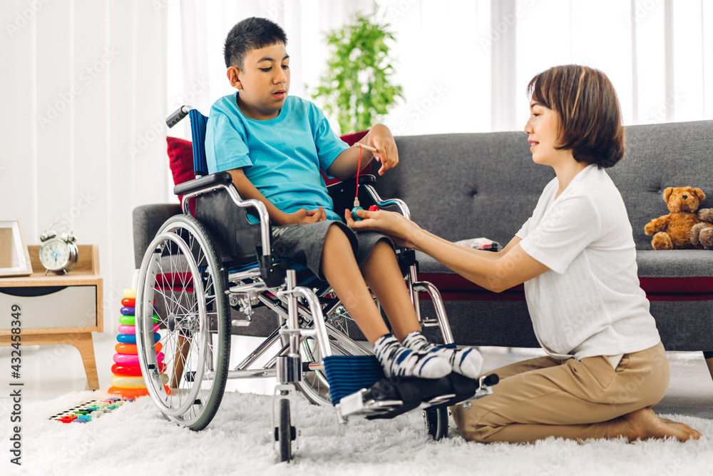 Portrait of asian physiotherapist carer helping and playing with special disabled child health problem by doing exercises sitting in wheelchair in rehabilitation clinic.disability care concept Portrait of asian physiotherapist carer helping and playing with special disabled child health problem by doing exercises sitting in wheelchair in rehabilitation clinic.disability care concept