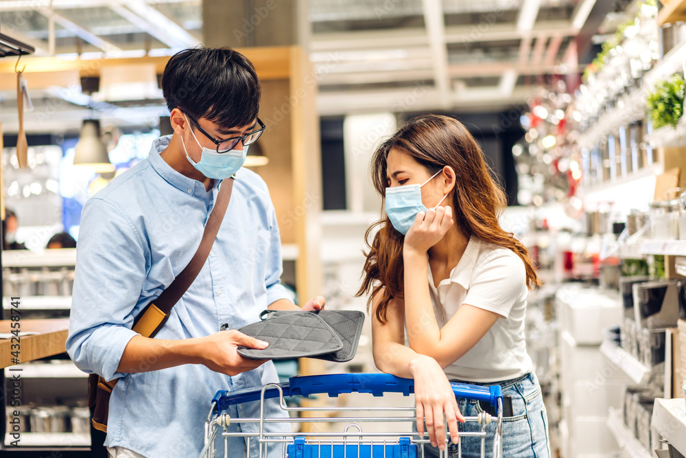 Young asian couple in quarantine for coronavirus wearing surgical mask face protection with social distancing shopping at store.covid19 and new normal concept