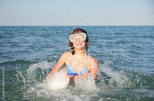 young caucasian girl plays in the sea water making splashes and jumps © ChiccoDodiFC