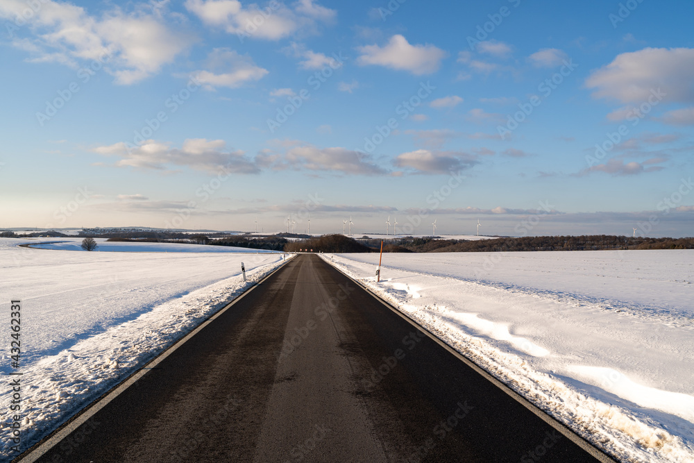 Road between snow with awesome blue cloudy sky 