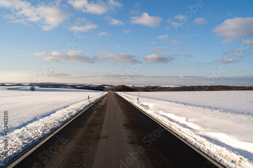 Road between snow with awesome blue cloudy sky 