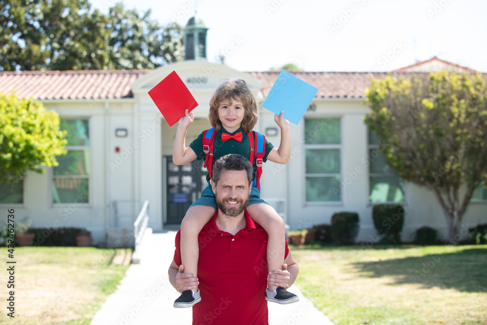 Obraz premium Outdoor school. Father giving son piggyback ride after school. Schoolboy going to school with father. Kids education.