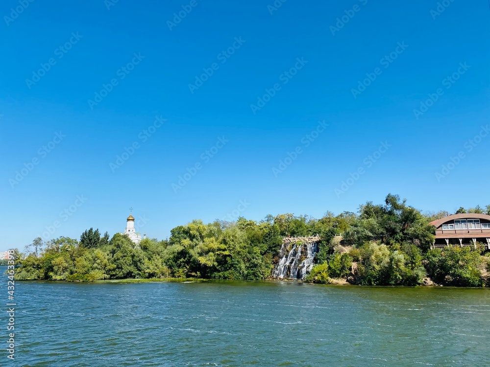 Island with a waterfall and a temple in the clear blue sky