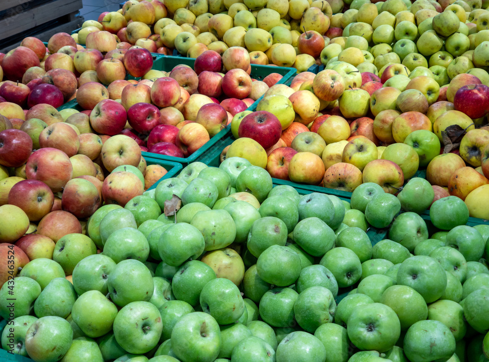 Red and green apples on the supermarket counter. Apples in the cardboard boxes on the grocery shelf. Red and green apples on the supermarket counter. Apples in the cardboard boxes on the grocery shelf.