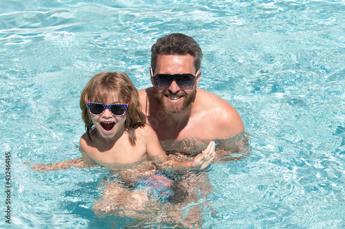 Father and son swimming in pool, summer family. Happy family in pool at summer weekend. Swimming lessons. Father son leisure.