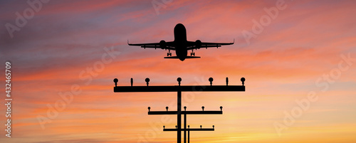 Silhouette of a plane landing at the airport against the background of sunset 