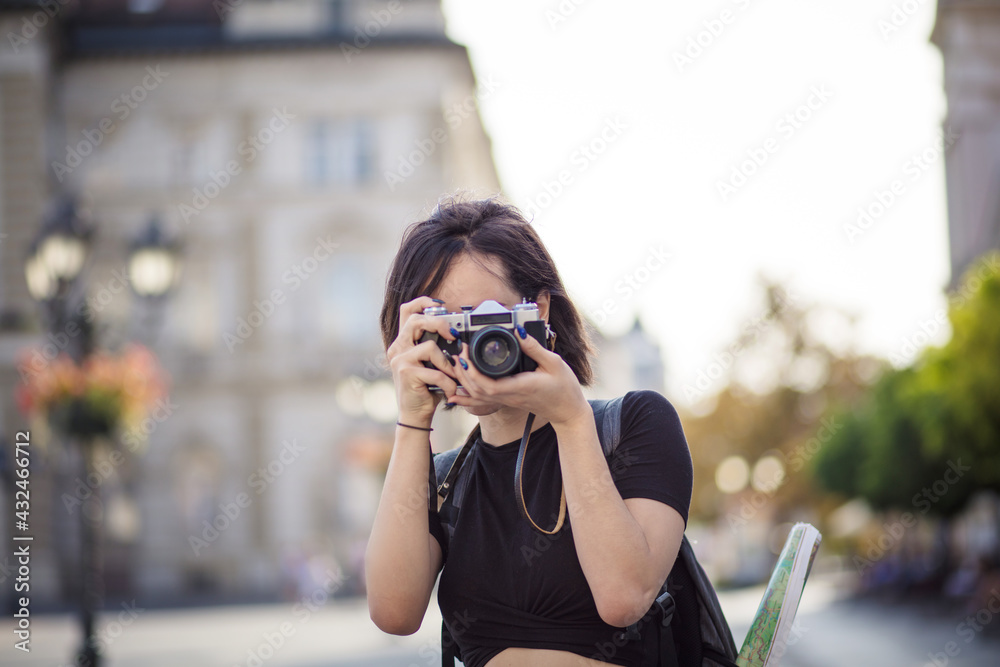 Young woman taking photo in the city with camera.