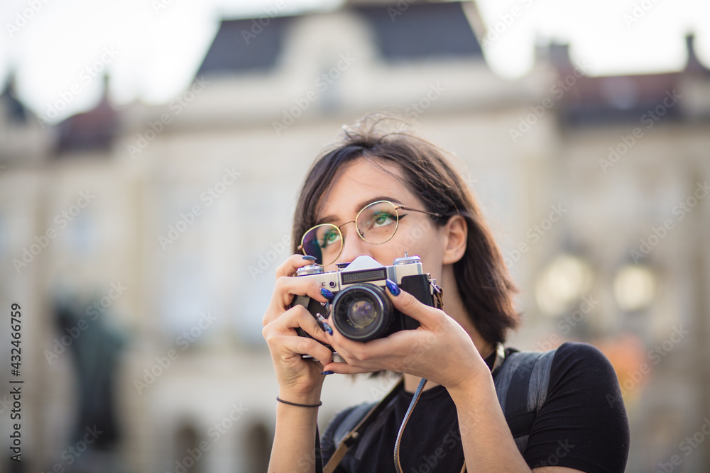 Young woman taking photo in the city with camera.