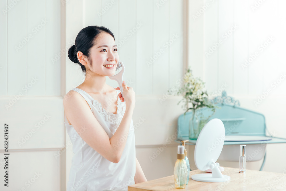 美顔ローラーを使う女性(笑顔)
美顔ローラーを使う女性(笑顔)