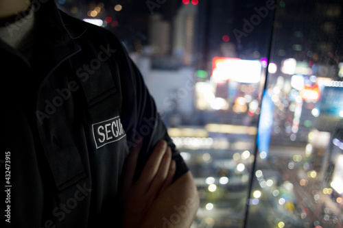 Security guard looking down city full of lights at night..