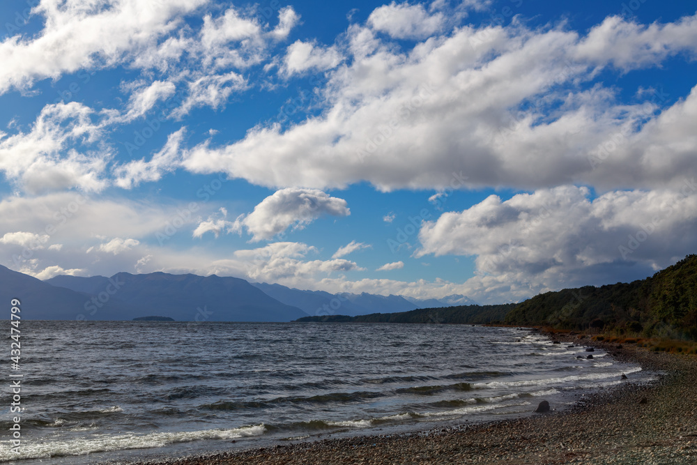 Lake Te Anau in Southland, New Zealand, the second largest lake in the country, with a sky full of fluffy white clouds above