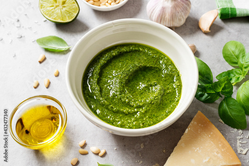 Fresh Italian pesto sauce with basil, pine nuts, parmesan cheese and olive oil on the light gray background. 