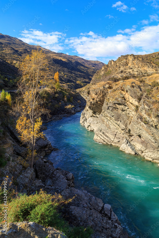 The Kawarau River in the South Island of New Zealand, passing through a narrow gorge with autumn trees on top of the cliffs 
