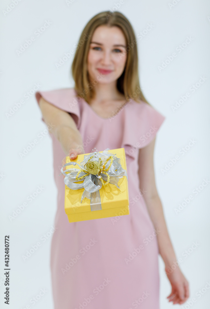 Portrait adult pretty caucasian woman blonde hair and pink dress look at camera holding present show a gift box and smile with white teeth look feel happy in studio with white background Portrait adult pretty caucasian woman blonde hair and pink dress look at camera holding present show a gift box and smile with white teeth look feel happy in studio with white background