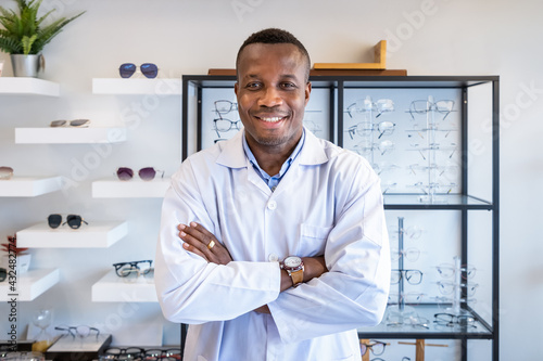 Portrait of African optician in optical shop store, cross arms, looking at camera. Eyecare concept. photo