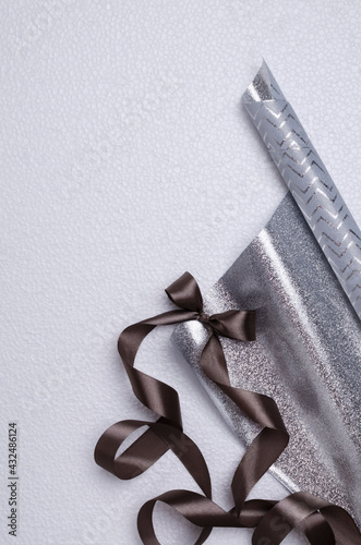 Top view of briwn ribbon and bow, silver paper for presents on the white surface.Empty space photo