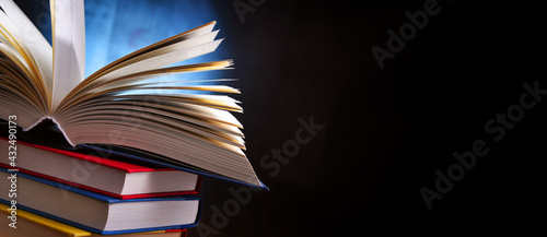 A composition with an open book lying on a stack of other books