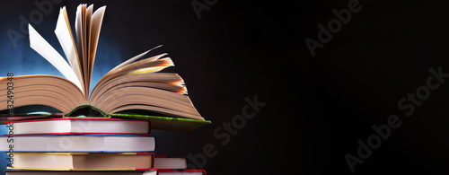 A composition with an open book lying on a stack of other books