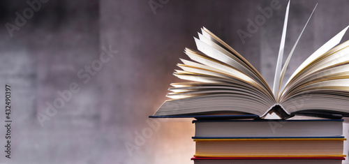 A composition with an open book lying on a stack of other books photo