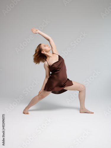 Fashion yoga model . Young woman doing yoga exercises indoors . Dress and jewelry