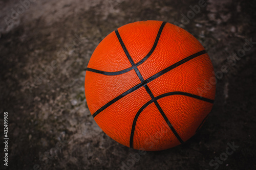 A dirty basketball on a concrete court after a street game. Dark background.