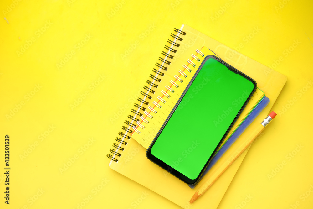 top view of smart phone and yellow color notepad on table top view of smart phone and yellow color notepad on table