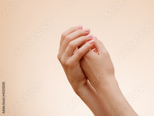 Closeup image of beautiful woman s hands with light pink French manicure on the nails . Skin care for hands  manicure and beauty treatment . Elegant and graceful hands with slender graceful fingers
