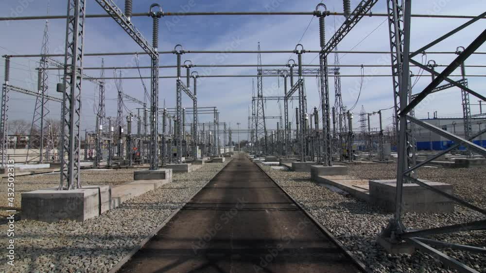 Motion along empty road under power transmission lines across distribution substation under blue sky with light clouds Motion along empty road under power transmission lines across distribution substation under blue sky with light clouds