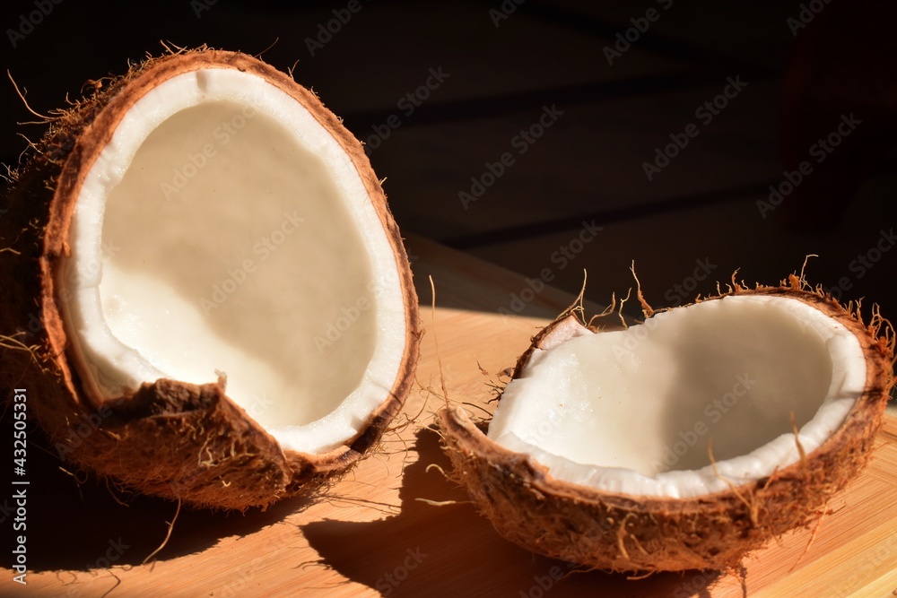 Coconut with half and leaves on wooden cutting board background Coconut with half and leaves on wooden cutting board background