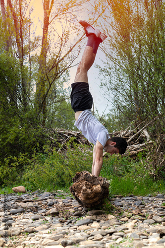 young teenager training in the field and performing balancing exercises on a fallen tree branch at sunset