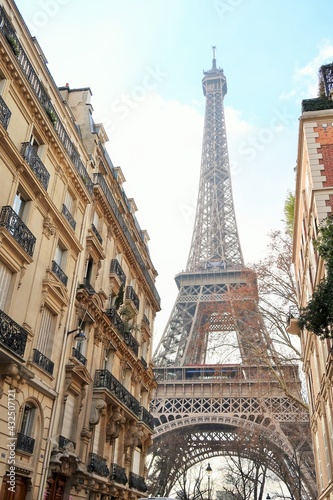 Immobilier ancien à Paris, rue avec un immeuble haussmannien et vue sur la tour Eiffel (France)