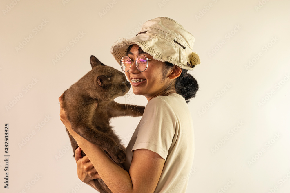Young happy beautiful Asian woman playing with burmese cat over ivory white background.